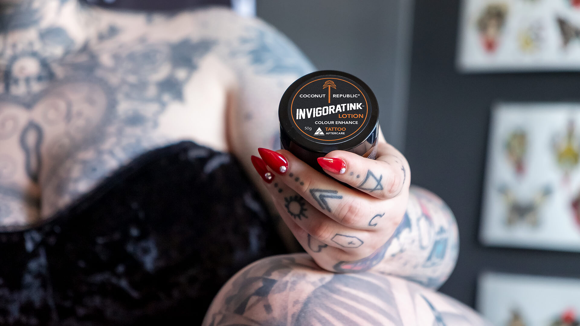 Tattooed woman holding Coconut Republic InvigoratINK Lotion